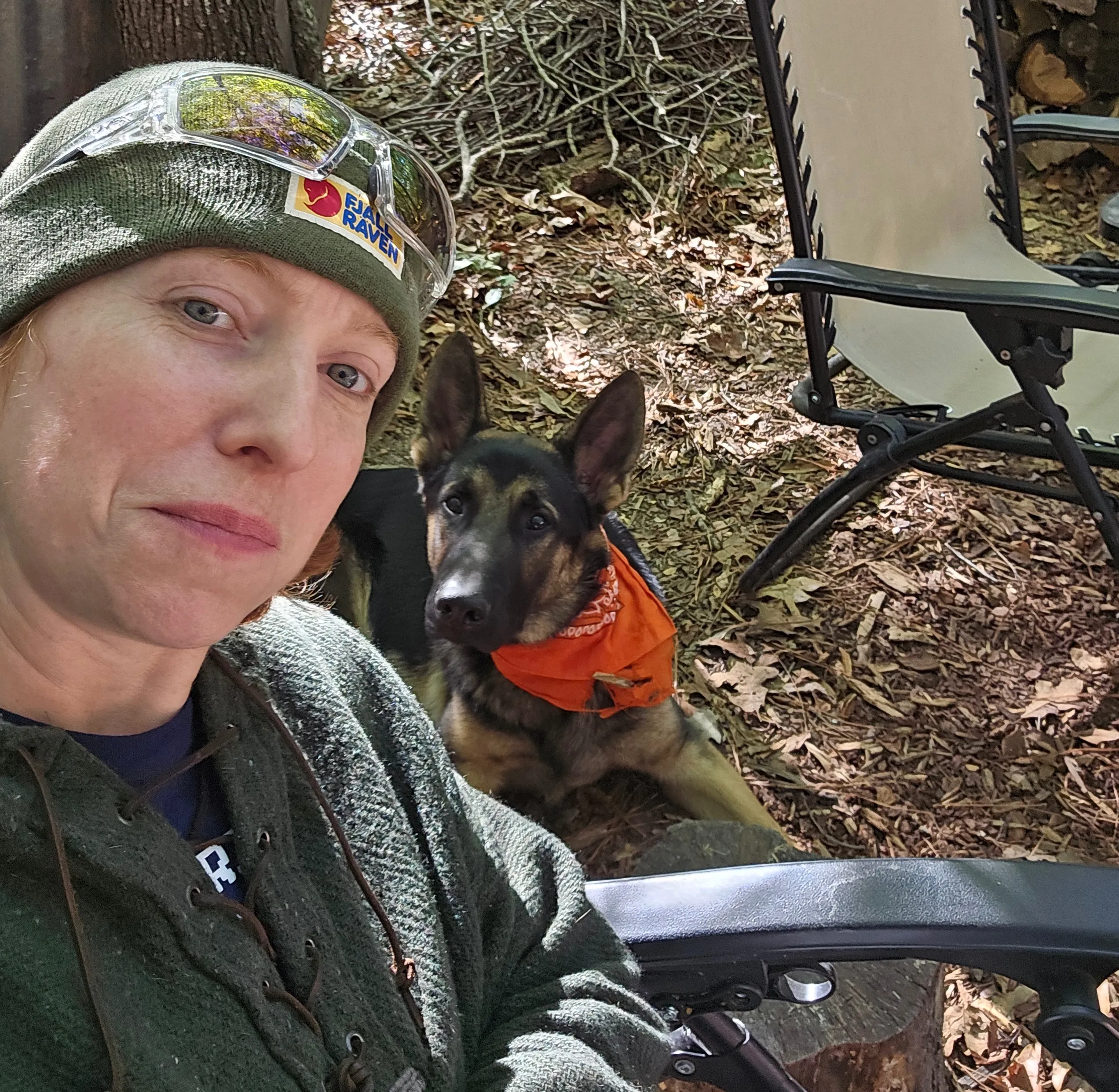 Georgia sitting in the woods with her German shepherd Grizz lying behind her.